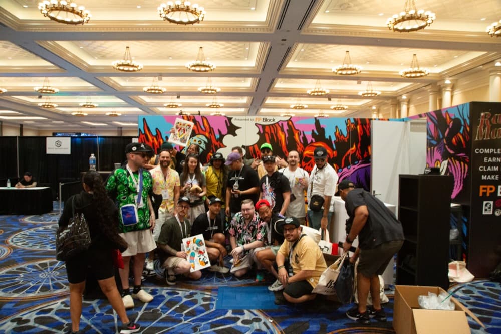 A crowd posing for a group photo at a sponsor booth